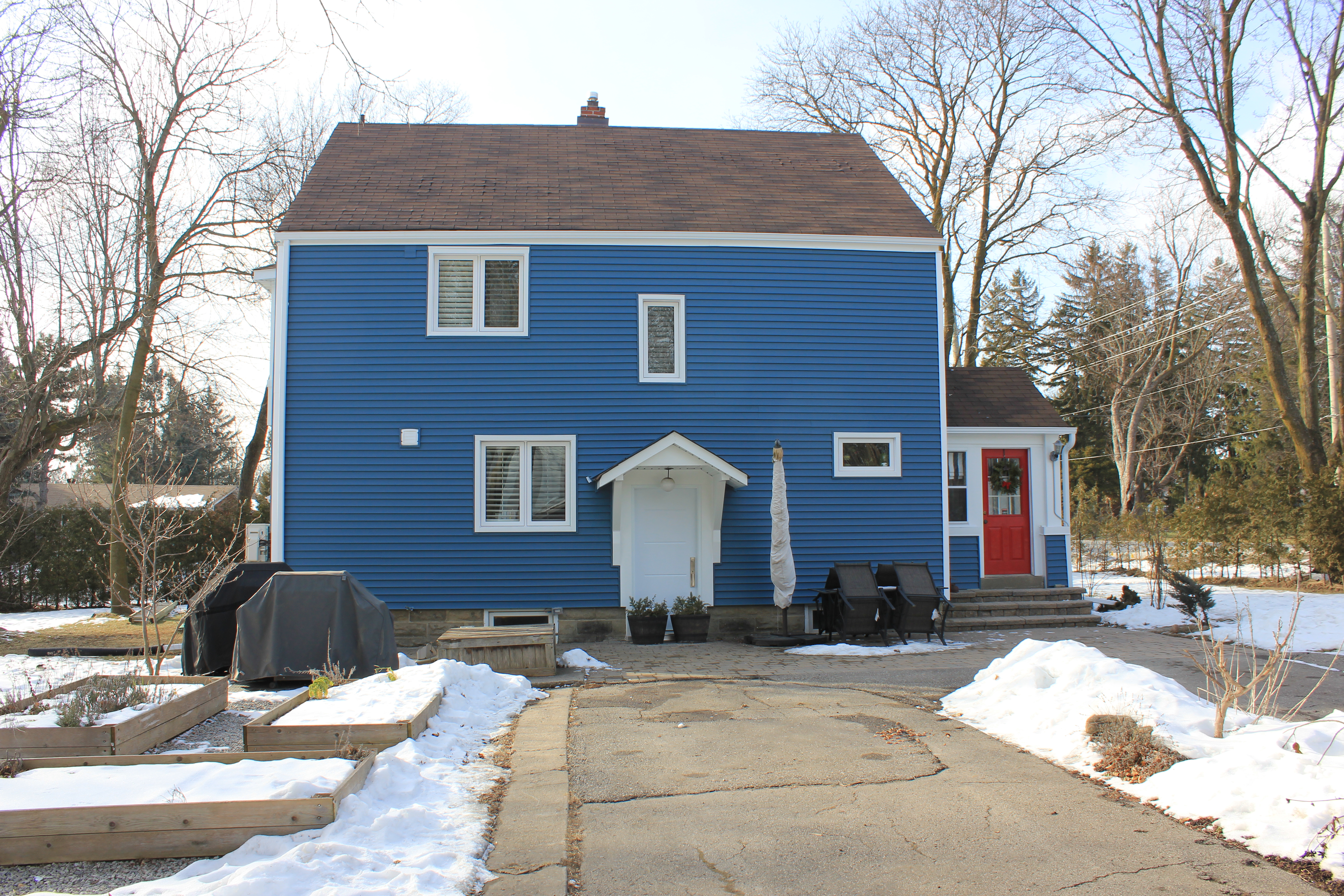 Two‑storey Markham home with new blue siding, white trim, updated soffit, fascia, and eavestroughs, shown in winter with driveway and outdoor patio furniture.