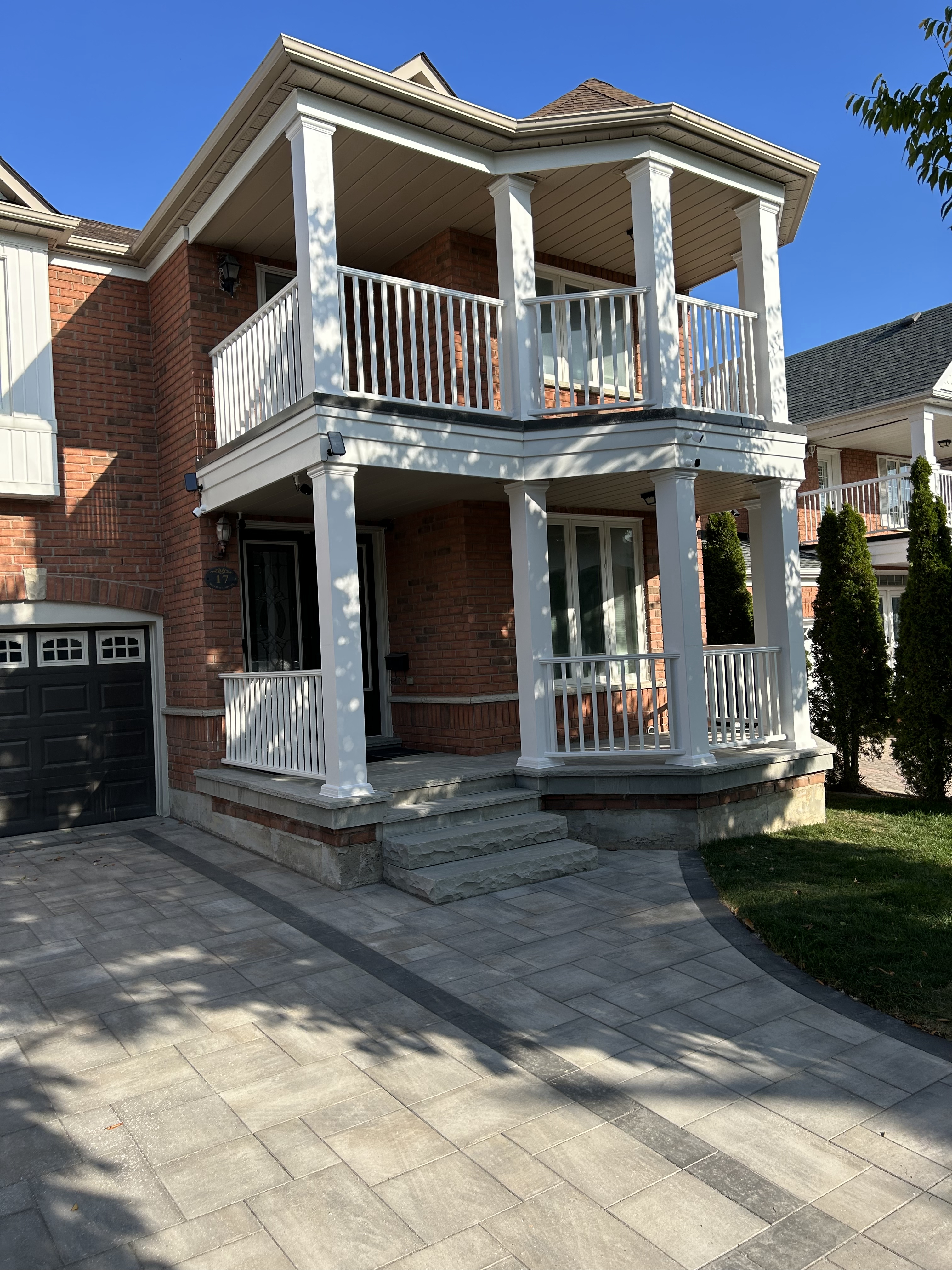 Two‑storey Markham home with restored exterior columns and updated railings on the upper and lower balconies, featuring white trim and brick exterior.
