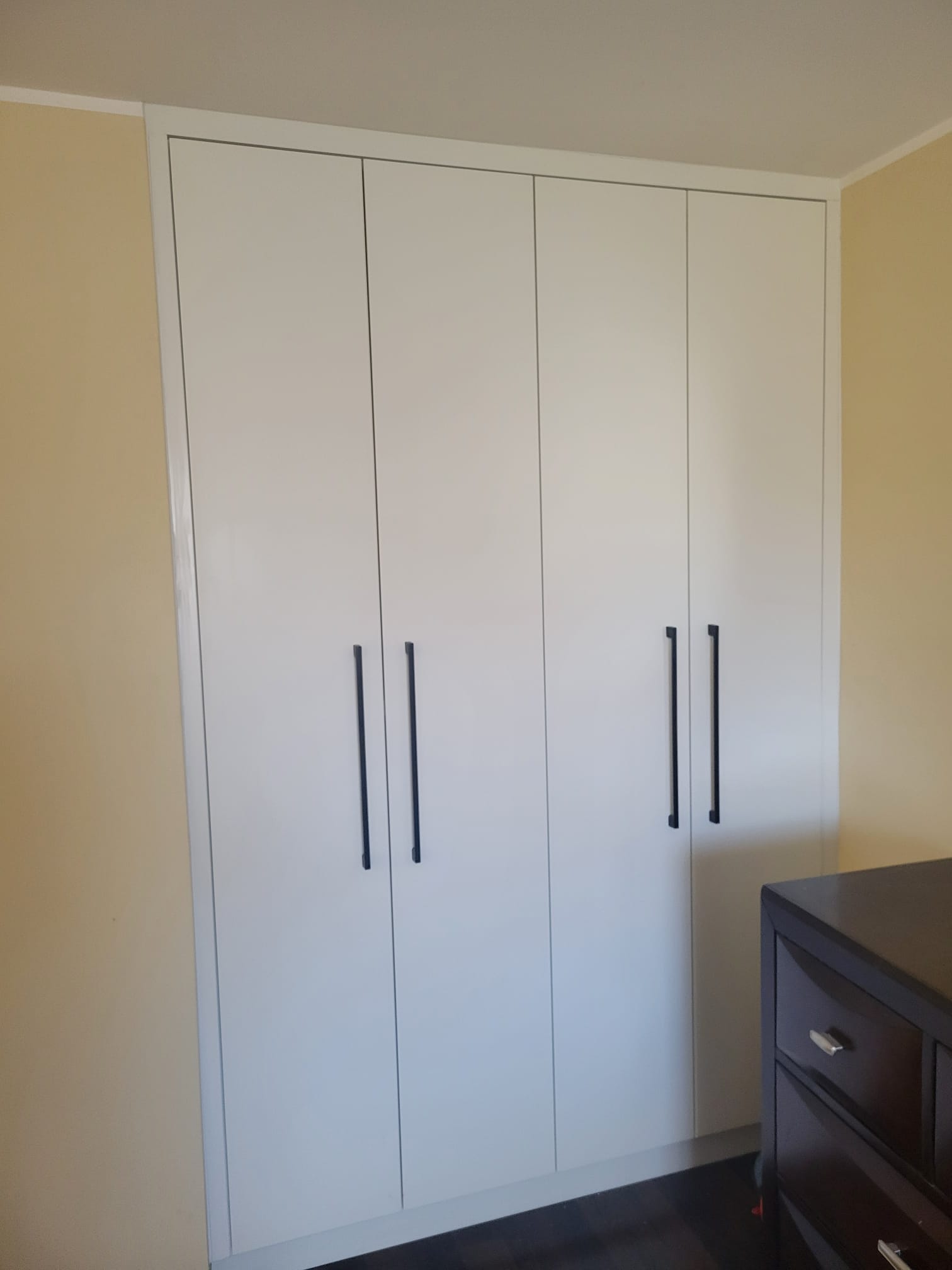 Custom white built‑in closet cabinets with full‑height doors, black handles, and organized interior shelving in a Toronto home.